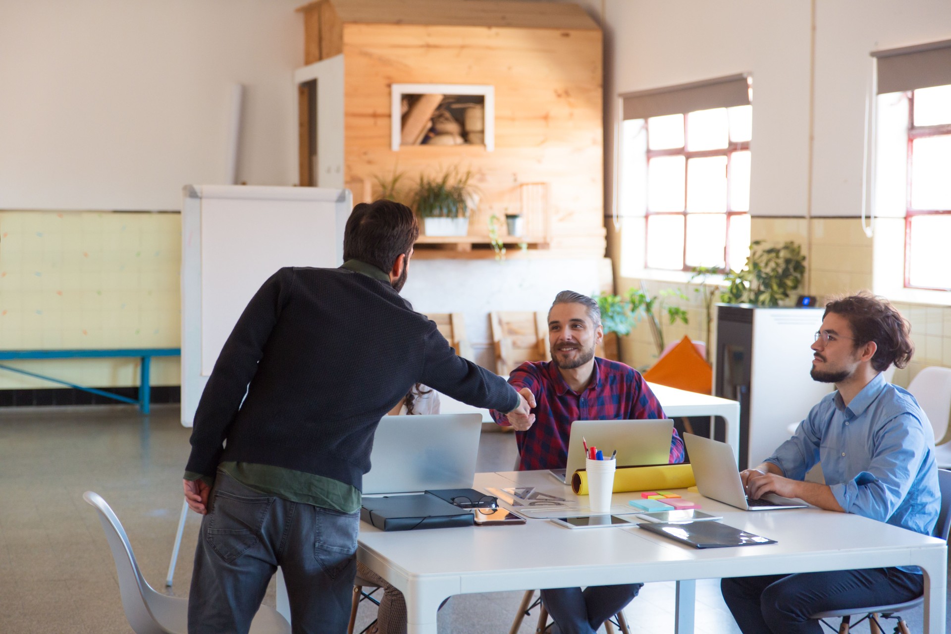 Équipe de démarrage s'asseyant ensemble, utilisant des ordinateurs portatifs, collègue de salutation pour débuter un atelier et une formation sur l'entrepreneuriat dans une salle de formation en location