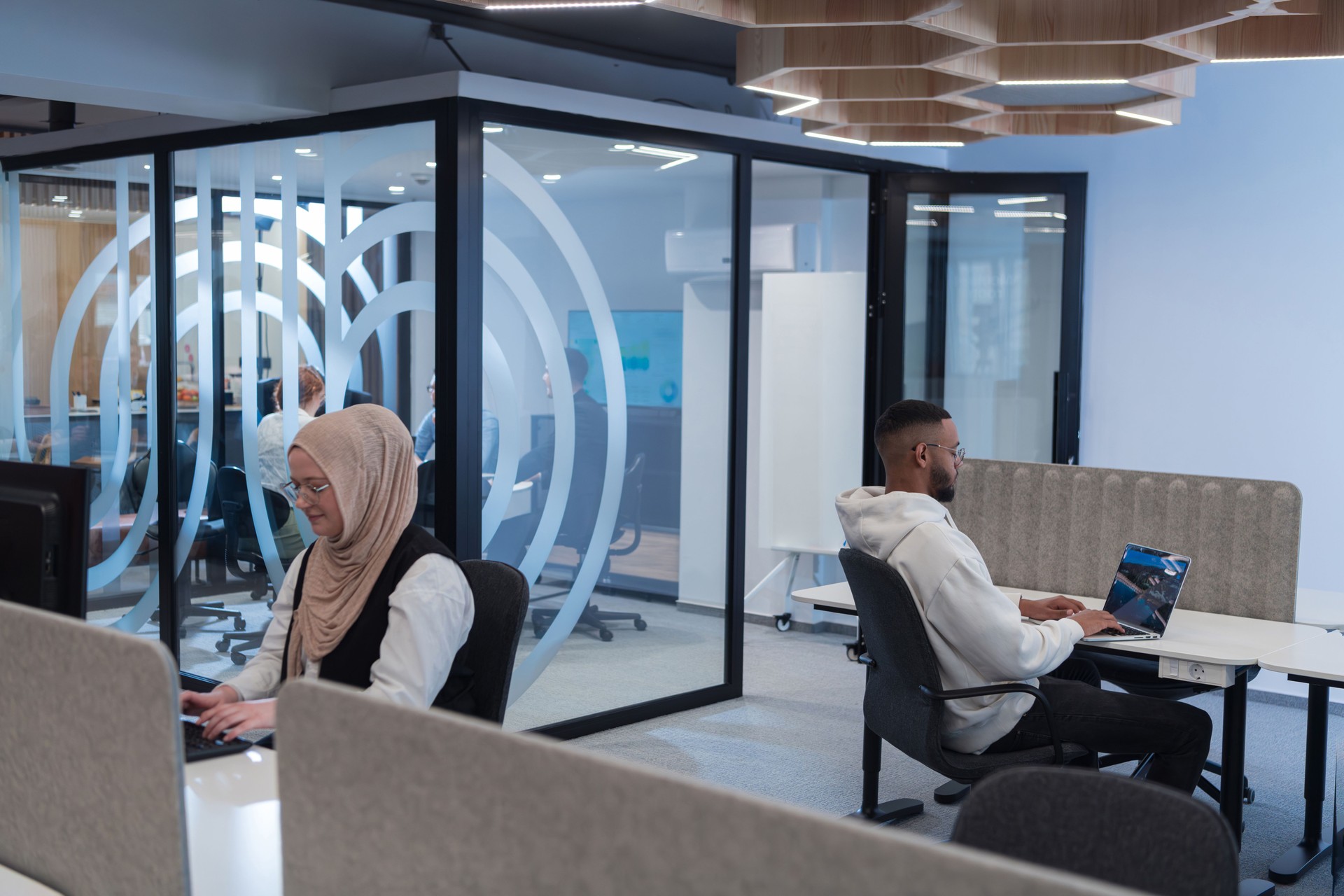Dans un environnement de bureau moderne, un homme d’affaires afro-américain et son collègue musulman, portant un hijab, s’engagent dans des discussions collaboratives, s’attaquent à diverses tâches commerciales et résolvent des problèmes ensemb